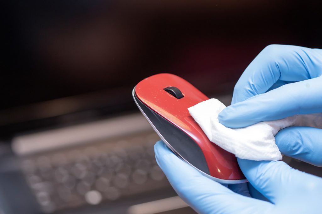 Hands cleaning laptop computer to avoid coronavirus infection